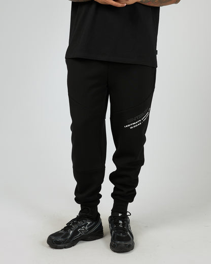 Male wearing black St Goliath jogger pants with St Goliath white text on a white background