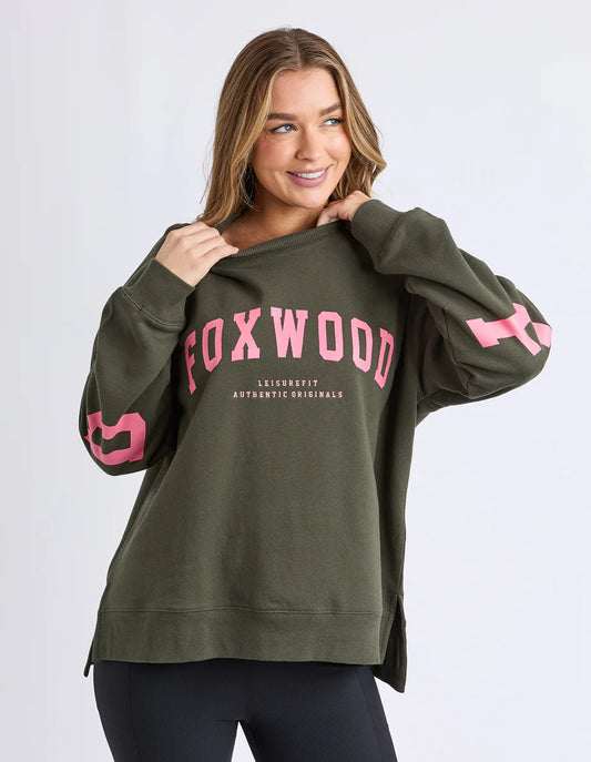 Woman wearing a green Foxwood Interval sweatshirt with pink text on a white background