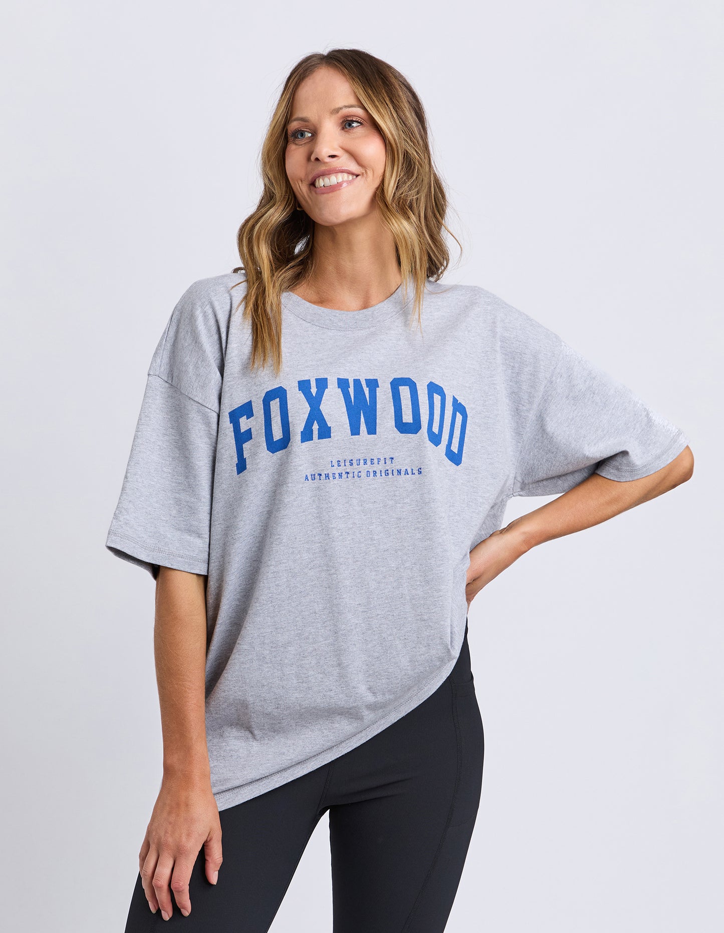 Woman wearing a gray Foxwood Interval t-shirt with 'FOXWOOD' printed on it against a white background