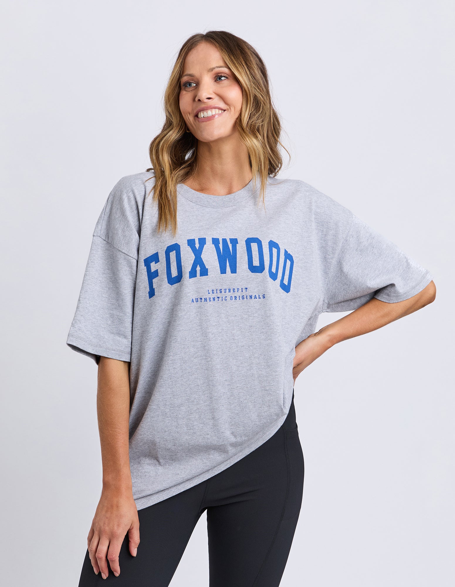 Woman wearing a gray Foxwood Interval t-shirt with 'FOXWOOD' printed on it against a white background