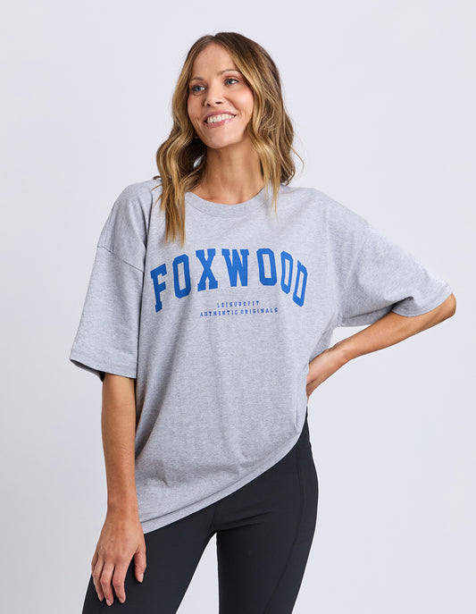 Woman wearing a gray Foxwood Interval t-shirt with 'FOXWOOD' printed on it against a white background