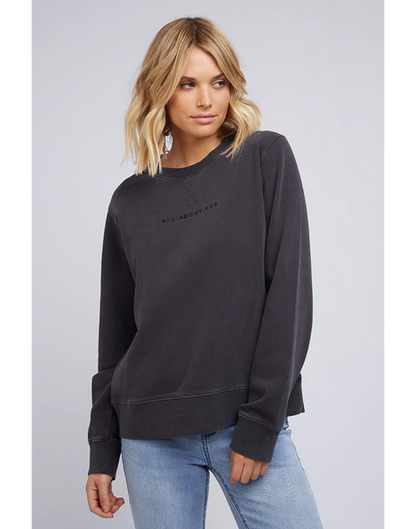 Woman wearing a All About Eve washed black sweatshirt with AAE Logo on a light gray background