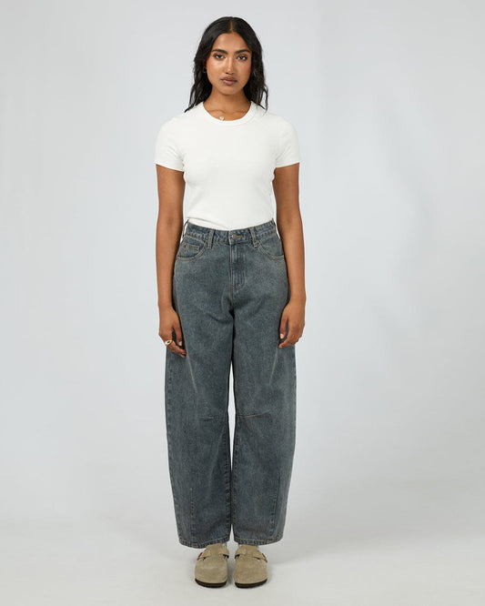 Person wearing a white AAE t-shirt and barrel jeans on a plain background