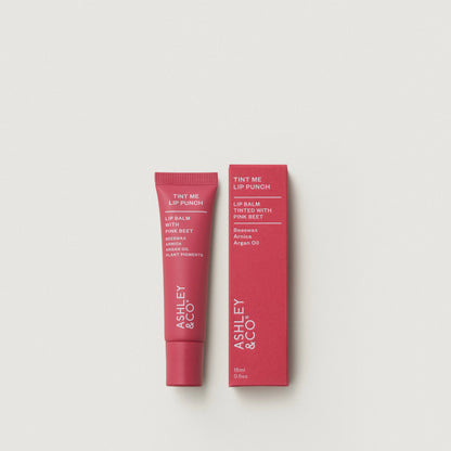 Lip balm tube and packaging with 'Ashley & Co' branding on a light gray background