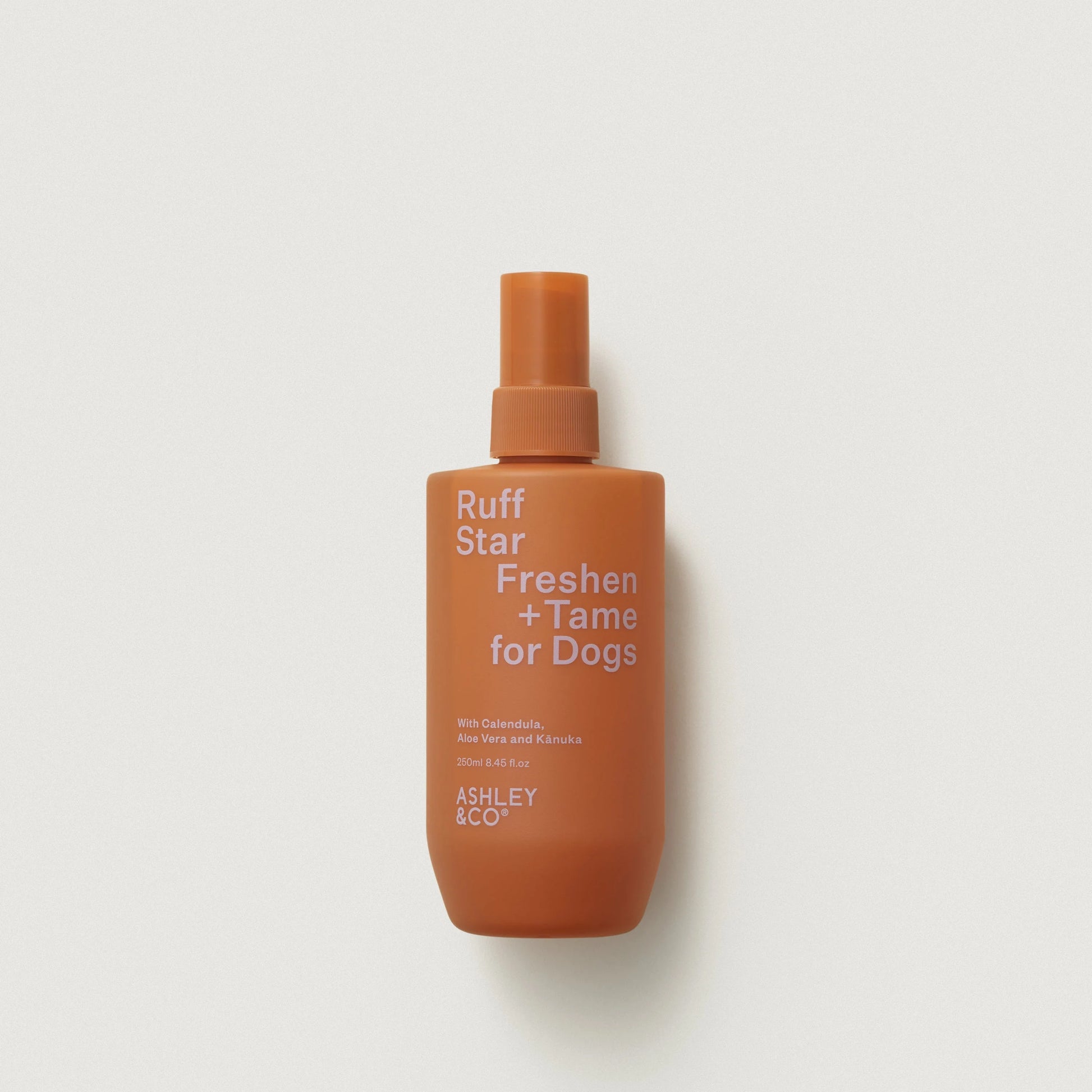 Orange bottle of 'Ruff Star Freshen + Tame for Dogs' by Ashley & Co on a light gray background