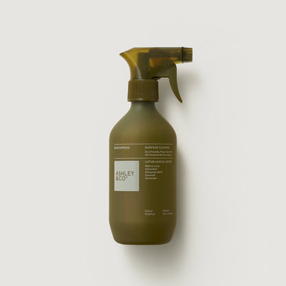 Olive green spray bottle with 'Ashley & Co.' label on a light gray background