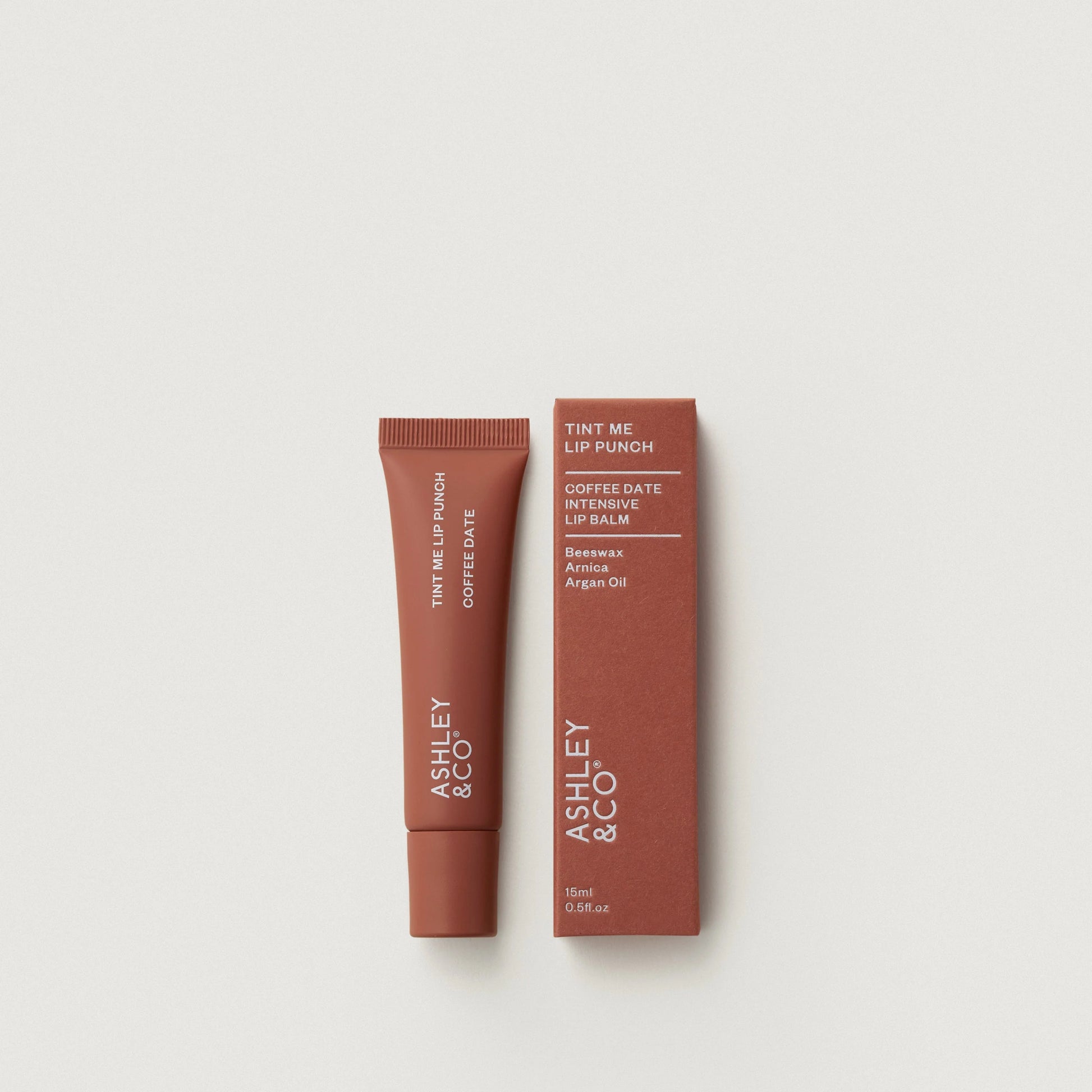 Lip balm and packaging with 'Ashley & Co' branding on a light gray background