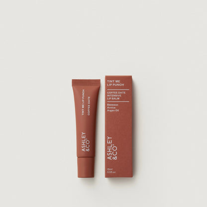 Lip balm and packaging with 'Ashley & Co' branding on a light gray background