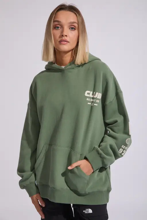 Person wearing a AAE All About Eve green hoodie with text on a plain background